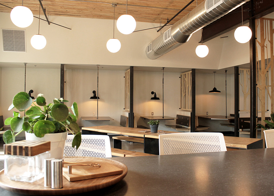 A coffeeshop-like coworking space, private booths line the walls with individual light fixtures and laser-cut wood partitions